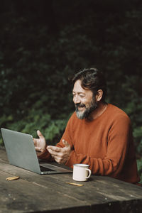 Smiling man talking on video call while sitting outdoors