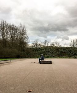 Man sitting on seat against sky