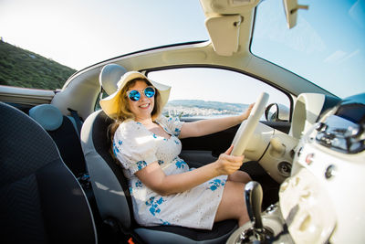 Portrait of smiling young woman using mobile phone while sitting in car