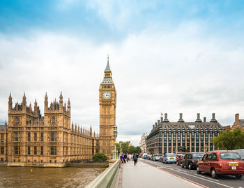 Westminster bridge by big ben over thames river against sky in city