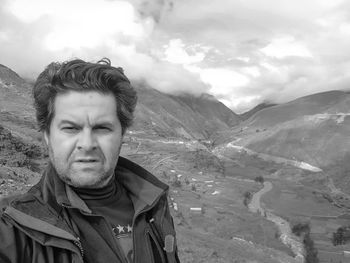 Man looking away while standing against mountains and sky