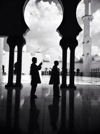 People in front of building against cloudy sky