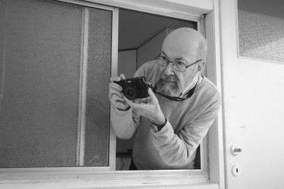 Side view of man photographing through window