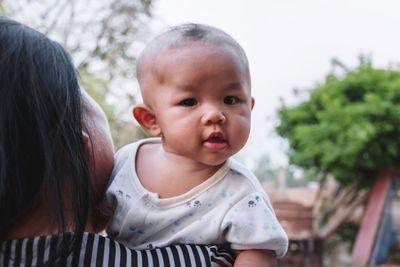 Rear view of mother carrying cute daughter against sky