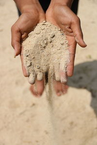 Low section of person spilling sand at beach