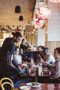 Male waiter serving food to customers in restaurant