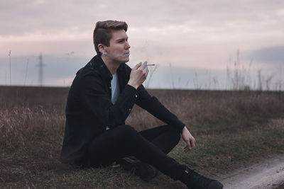 Young man using mobile phone while sitting on field