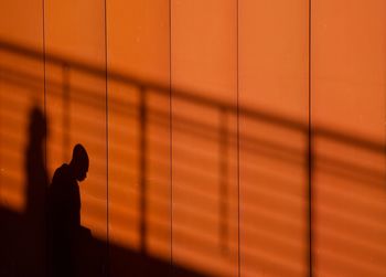 Silhouette man standing against wall