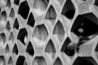 Cropped hands of woman amidst patterned wall