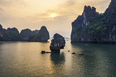 Rocks in sea against sky during sunset