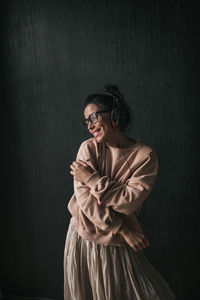 Portrait of young woman standing against wall