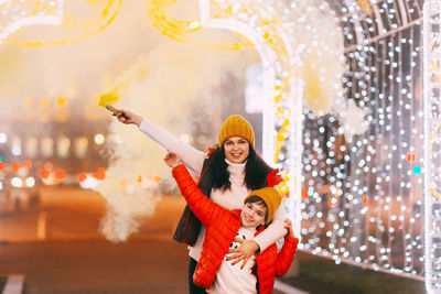 Mom and her son hold colored smoke bombs in their hands during the celebration of christmas 