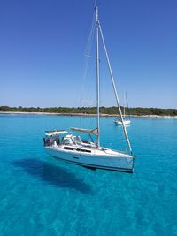 Sailboat sailing on sea against clear blue sky