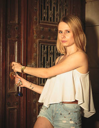 Portrait of young woman opening door