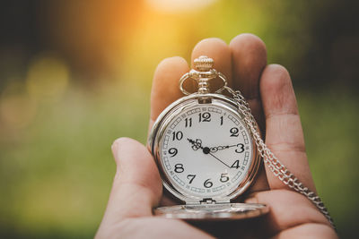 Close-up of hand holding pocket watch outdoors