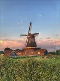 Traditional windmill on field against sky during sunset