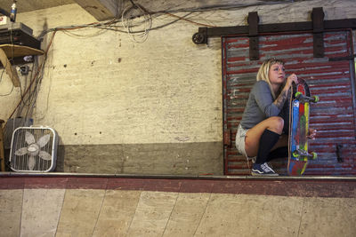 Full length of woman sitting on staircase against wall