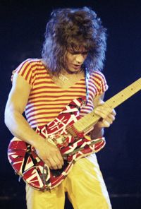 Young woman playing guitar against black background