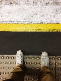 Low section of person standing on yellow umbrella