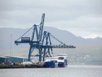 Cranes at commercial dock against sky