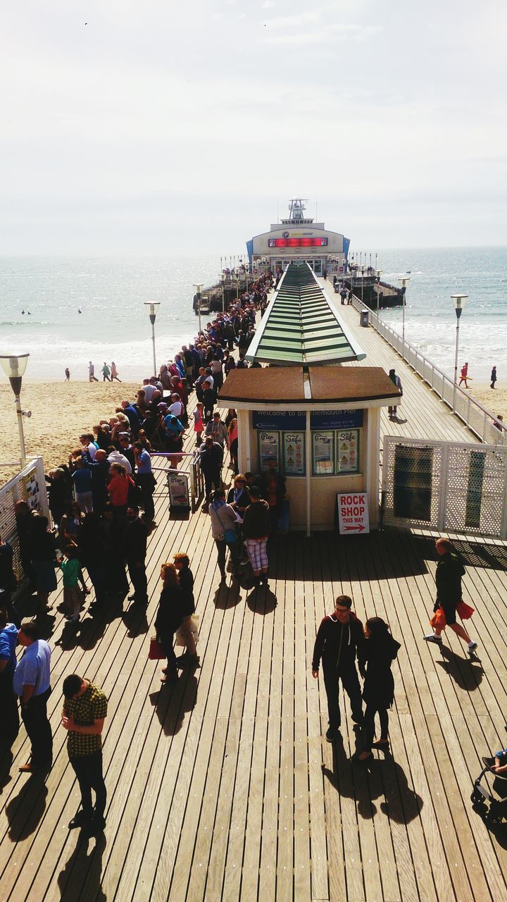 sea, beach, horizon over water, large group of people, water, shore, person, sky, mixed age range, men, lifestyles, built structure, sand, leisure activity, architecture, vacations, walking, building exterior, high angle view