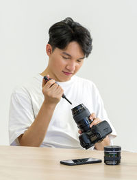Portrait of young woman photographing on table