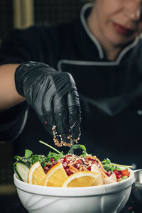 Chef in restaurant, seasoning salad with sesame