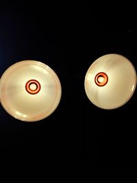 Close-up of illuminated light bulb over black background