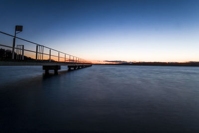 Bridge over river against sky at sunset