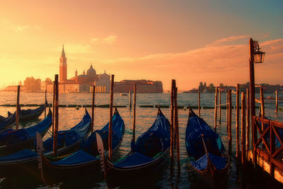 Gondolas moored in grand canal against st mark square against sky during sunset