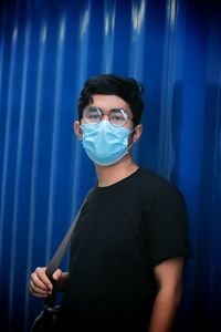 Portrait of young man standing against blue wall