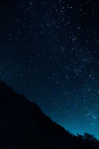 Low angle view of silhouette mountain against sky at night