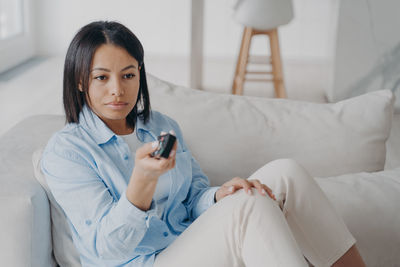 Young woman using mobile phone while lying on bed at home