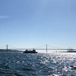 View of suspension bridge over sea against clear sky