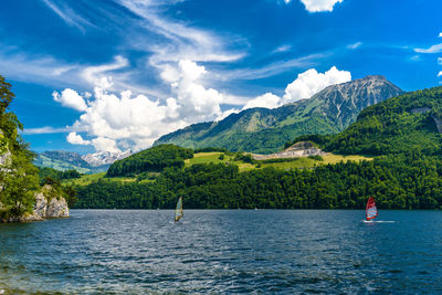 Scenic view of sea by mountain against sky