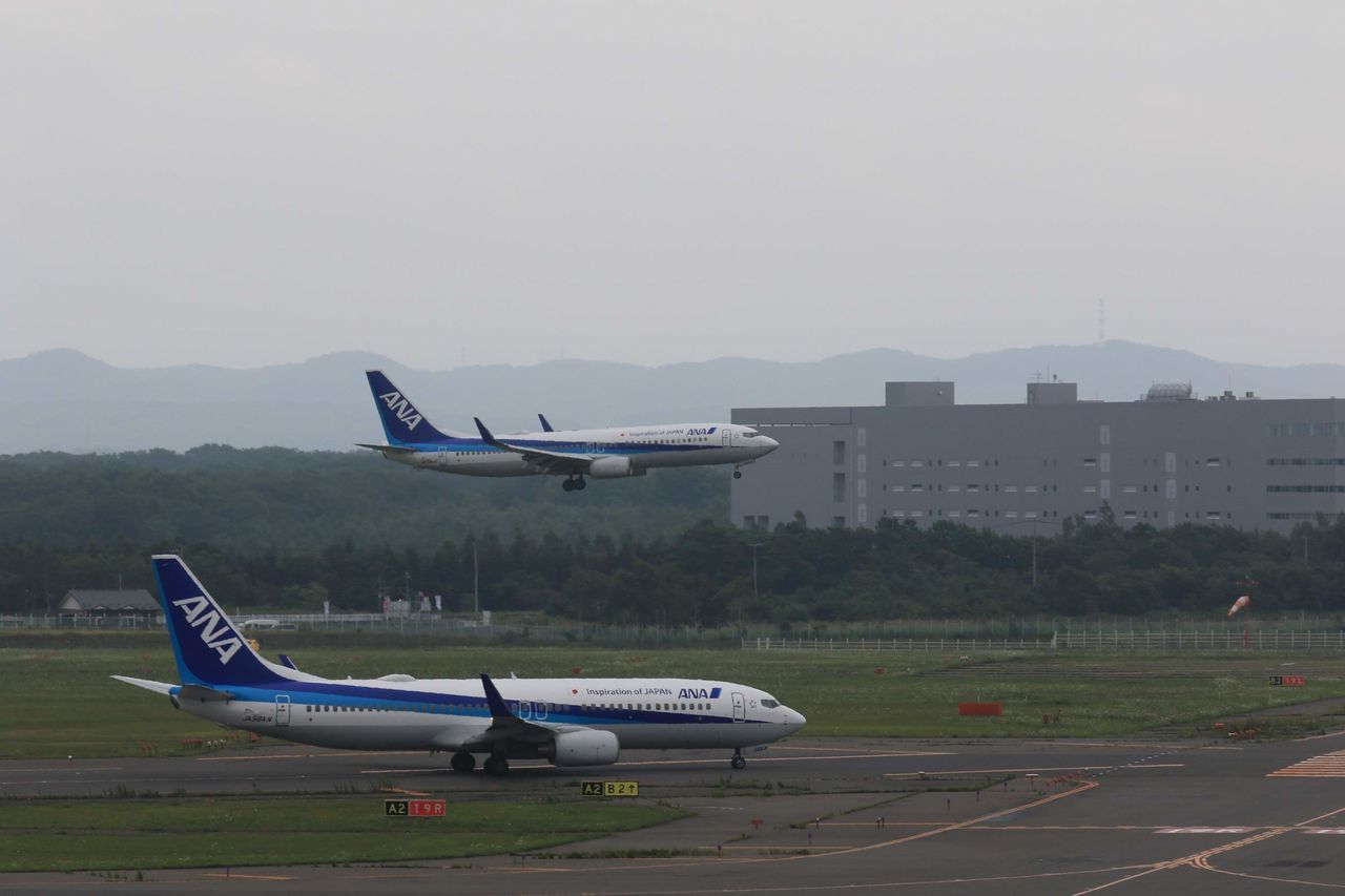 SIDE VIEW OF AIRPLANE ON AIRPORT AGAINST SKY