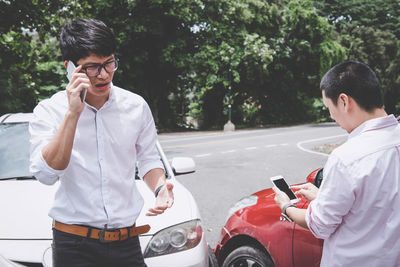 Young man using mobile phone on road in city