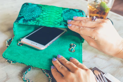 Midsection of woman holding smart phone on table