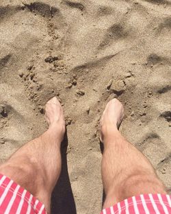 Low section of man standing on sandy beach