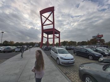 Woman standing on street against sky in city