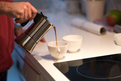 Close-up of hand pouring coffee in cup