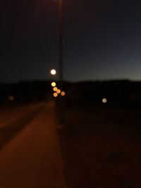 Illuminated road against sky at night