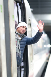 Man waving hand while standing in train