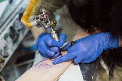 High angle view of tattoo artist making tattoo on customer hand