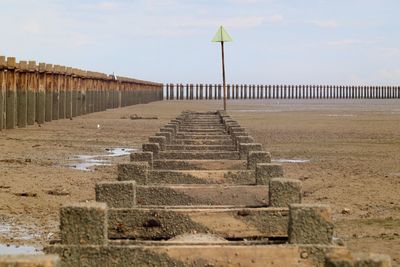 Footpath leading towards beach against sky