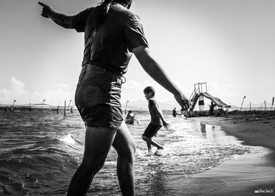 Friends enjoying at beach against sky