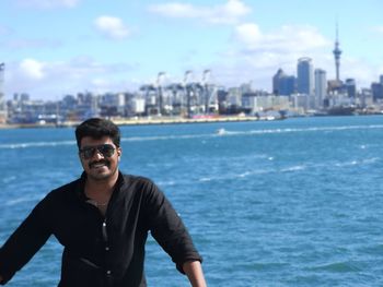 Portrait of smiling man in sunglasses standing against sea