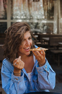 Portrait of young woman eating margarita pizza