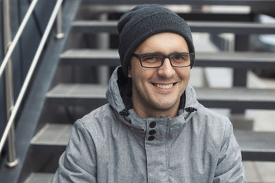 Portrait of smiling man sitting on steps outdoors