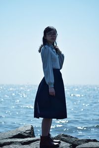 Woman standing on beach against clear sky